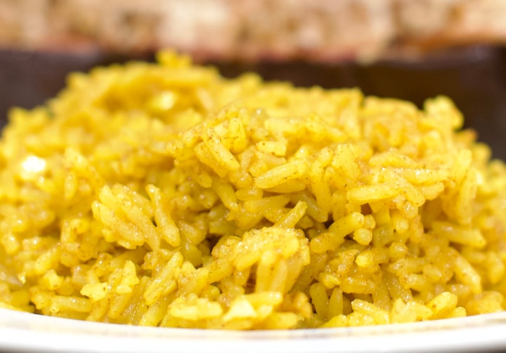 Um montinho de arroz amarelado dentro de um prato branco