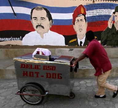 A street vendor pushes his cart past a mural depicting Venezuela's late President Hugo Chavez (C), Cuba's former leader Fidel Castro and Nicaragua's President Daniel Ortega (L), in Managua March 6, 2013. Chavez died on Tuesday at 58 after a two-year battle with cancer that was first detected in his pelvis. REUTERS/Inti Ocon (NICARAGUA - Tags: OBITUARY SOCIETY BUSINESS)