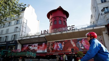 Um ciclista passa pelo Moulin Rouge, o cabaré mais famoso de Paris, depois que as pás do famoso moinho vermelho caíram durante a noite  