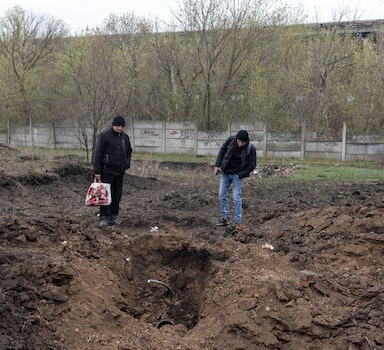 Pessoas olham para uma cratera aberta por um míssil Kalibr em Kramatorsk, Ucrânia