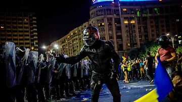 Um homem confronta policiais durante protesto contra o governo romeno em Bucareste. Foto: Andrei Pungovschi / AFP
