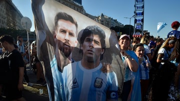 A flag featuring Lionel Messi, left, and the late soccer great Maradona hangs amid Argentina soccer fans after they watched the team's World Cup semifinal win over Croatia, hosted by Qatar, on a screen set up in the Palermo neighborhood of Buenos Aires, Argentina, Tuesday, Dec. 13, 2022. (AP Photo/Gustavo Garello). Foto: Gustavo Garello/AP