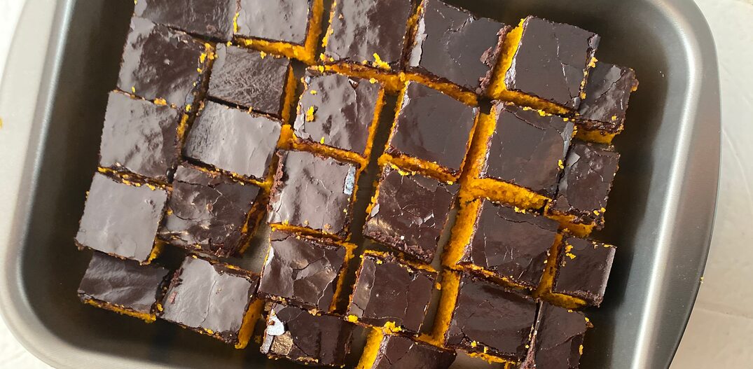 Em uma forma de metal quadrada está um bolo de cenoura com cobertura de chocolate cortado em quadradinhos. Foto: Daniel Teixeira/Estadão