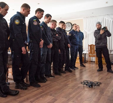 O piloto de drones Chase Bailey explica aos membros do serviço de emergência ucraniano como operar o drone Lemur