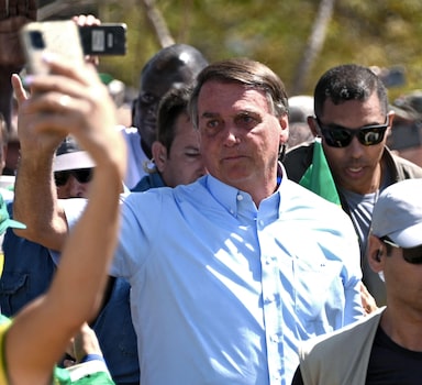 Brazilian President Jair Bolsonaro (R) greets supporters demonstrating their support for him and his controversial ally, deputy Daniel Silveira, who Bolsonaro pardoned after the Supreme Court had sentenced him to prison time for his role leading a movement calling for the court to be overthrown, in Brasilia on May Day, on May 1, 2022. (Photo by EVARISTO SA / AFP)