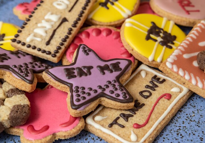 Biscoitos coloridos com escritas Eat Me e Take One em chocolate