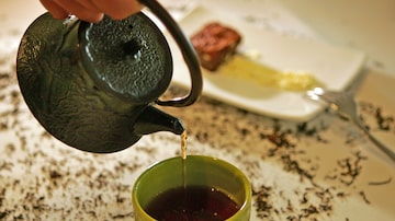 Bule de chá preto servindo xícara amarela com chá. Foto: HÉLVIO ROMERO