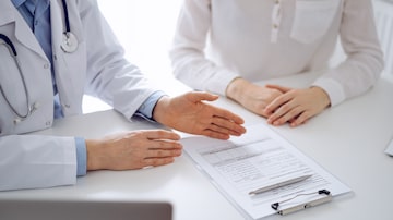 Doctor and patient discussing current health questions while sitting near of each other and using clipboard at the table in clinic, just hands closeup. Medicine concept. Foto: rogerphoto/Adobe Stock