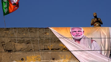 Um policial vigia do telhado de um prédio durante um comício de campanha do primeiro-ministro indiano Narendra Modi antes das eleições parlamentares em Ghaziabad, Índia