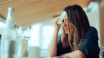 Woman Wiping Sweaty Forehead Using a Napkin. Lady suffering from hot flashes due to early menopause symptoms. Foto: nicoletaionescu/Adobe Stock 