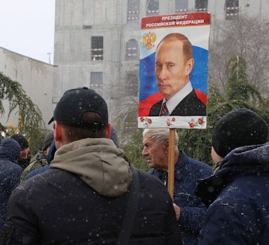 A man holds a portrait of Russian President Vladimir Putin during celebrations of the eighth anniversary of Russia's annexation of Crimea in Simferopol, Crimea March 18, 2022. REUTERS/Alexey Pavlishak