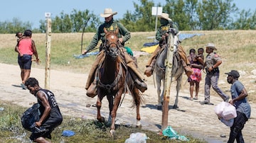 Montado a cavalo, agente da Patrulha de Fronteira dos EUA tenta impedir migrantes haitianos de chegarem a solo americano. Foto: PAUL RATJE / AFP