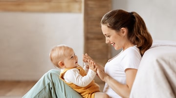 Love and tenderness, motherhood concept. Loving young mother caressing her cute baby boy, sitting on floor by bed, side view. Caucasian woman bonding with little kid at home, copy space. Foto: Prostock-studio/Adobe Stock