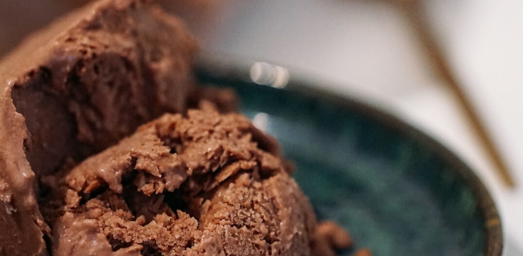 Prato verde com uma bola de sorvete de chocolate dentro. Foto: Unsplash | Banco de Imagens