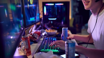 Teenage Boy Drinking Caffeine Energy Drink Gaming At Home Using Dual Computer Screens At Night. Foto: div