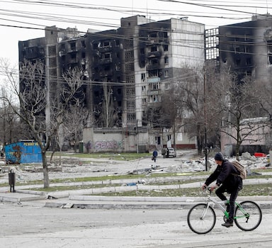 A man rides a bicycle near residential buildings destroyed in the course of Ukraine-Russia conflict in the southern port city of Mariupol, Ukraine April 1, 2022. REUTERS/Alexander Ermochenko