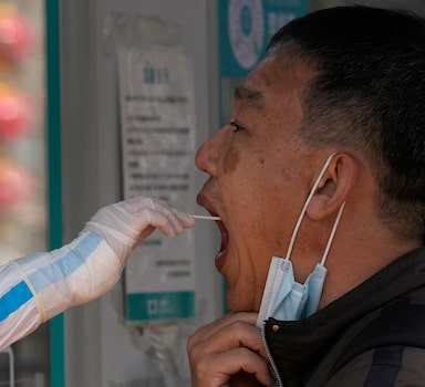 FILE - A worker takes a swab sample for a COVID-19 test at a mobile testing site on Tuesday, March 15, 2022, in Beijing. China's national health authorities reported two COVID-19 deaths on Saturday, the first recorded rise in the death toll since January 2021, as the country battles an omicron-driven surge. (AP Photo/Ng Han Guan, File)
