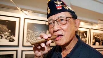 FILE - Former Philippine President Fidel Ramos bites his cigar as he looks on photographs during an exhibit on the 20th anniversary of "People Power" in suburban Makati, south of Manila, Philippines, on Feb. 22, 2006. Ramos, a U.S.-trained ex-general who saw action in the Korean and Vietnam wars and played a key role in a 1986 pro-democracy uprising that ousted a dictator, has died. He was 94. Some of Ramos's relatives were with him when he died on Sunday, July 31, 2022, said his longtime aide Norman Legaspi. (AP Photo/Aaron Favila, File). Foto: AARON FAVILA