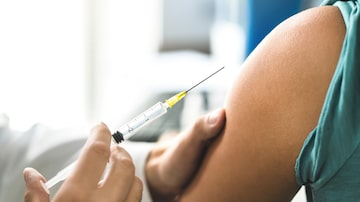 Doctor giving vaccine, flu or influenza shot  to patient with injection needle. Close up of arm and medical professional. Nurse or physician with syringe. Immunity, HPV or health care concept. Foto: terovesalainen/Adobe Stock