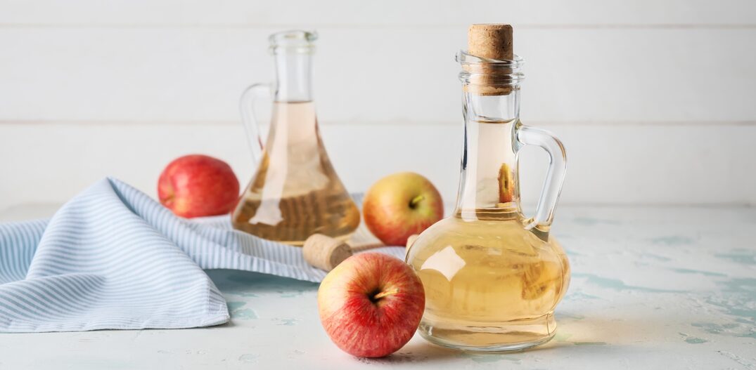 Bottles of apple cider vinegar on white table. Foto: Pixel-Shot/Adobe Stock    