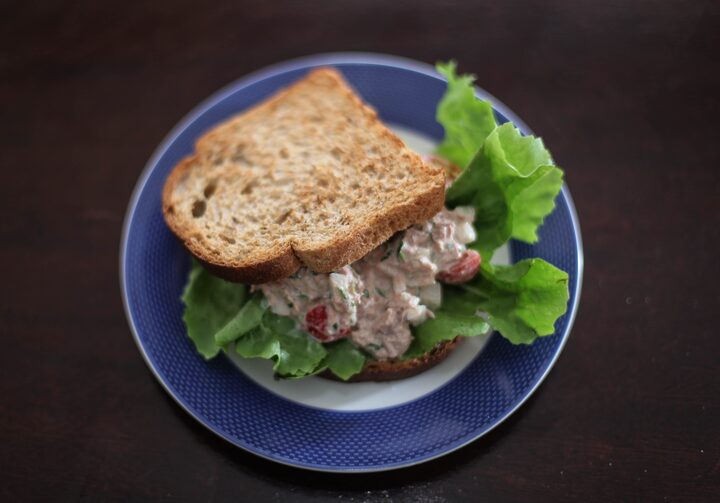Prato azul com sanduíche de atum recheado com alface e tomate