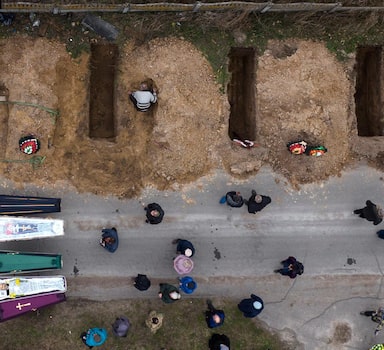 The bodies of four people who died during the Russian occupation await burial during funerals in Bucha, on the outskirts of Kyiv, Wednesday, April 20, 2022. (AP Photo/Emilio Morenatti)