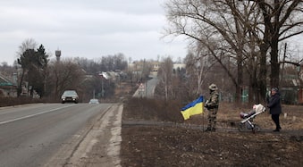 Garoto segura uma metralhadora de brinquedo ao lado de uma bandeira da Ucrânia. Foto de  Anatolii Stepanov/AFP