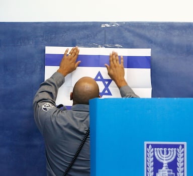 An official adjusts a poster of the Israeli flag at a polling station in Rosh Haayin, Israel, on Tuesday, Sept. 17, 2109. MUST CREDIT: Bloomberg photo by Kobi Wolf.