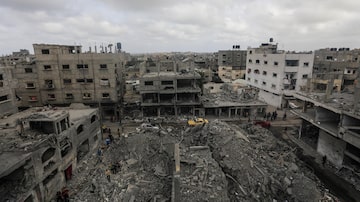 Palestinos buscam por corpos e sobreviventes entre os escombros de uma casa destruída após um ataque aéreo israelense no campo de refugiados de Al Nusairat, no sul da Faixa de Gaza, em 27 de abril de 2024