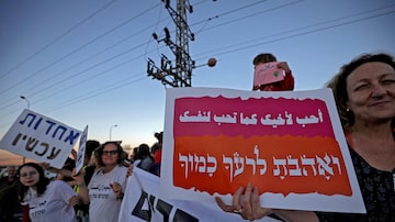 Manifestação na cidade mista de Jish com cartaz com a frase da Tora 'ame seu vizinho como a si mesmo', em árabe e em hebraico. Foto: Jalaa Marey/AFP