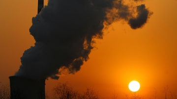 O sol se põe ao lado de uma chaminé de uma usina de energia a carvão em Pequim