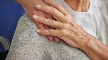Comfort, hand and nurse with senior for care in wheelchair at house, nursing home or retirement. Zoom, hands and touch on shoulder for compassion, elderly and support for healthcare in disability. Foto: Beaunitta V W/peopleimages.com/Adobe Stock