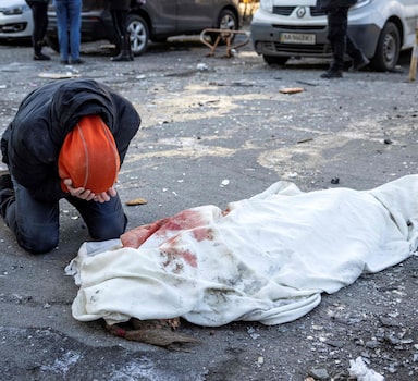 EDITORS NOTE: Graphic content / TOPSHOT - A person mourns next to a wrapped body near a residential building which was hit by the debris from a downed rocket in Kyiv on March 17, 2022. - One person was killed and three injured when debris from a downed rocket hit a Kyiv apartment block, as Russian forces press in on the capital, emergency services said. Russian troops trying to encircle Kyiv have launched early morning strikes on the city for several successive days, putting traumatised residents further on edge. (Photo by FADEL SENNA / AFP)