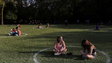 Mulheres sentadas em um campo onde foram pintados círculos para ajudar os visitantes a manter o distanciamento social no Parque Ibirapuera após a reabertura. Foto: REUTERS/Amanda Perobelli