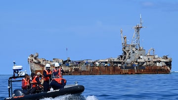 Funcionários da Guarda Costeira das Filipinas filmam o navio de guerra BRP Sierra Madre, que está atracado no Mar do Sul da China, em uma região disputada pelas Filipinas e pela China 
