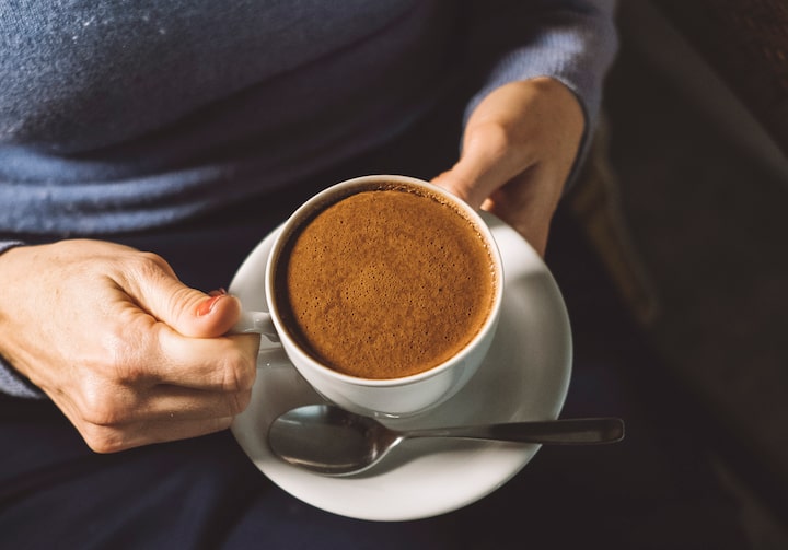 Mãos femininas segurando xícara com chocolate quente dentro