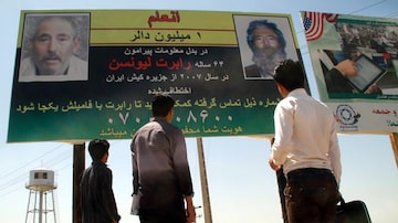 Afegãos olham para um outdoor prometendo recompensa por informações sobre o ex-agente do FBIRobert Levinson, em Herat, perto da fronteira com o Irã, no Afeganistão, em 2012. Foto: Jalil Reazayee/EFE/EPA