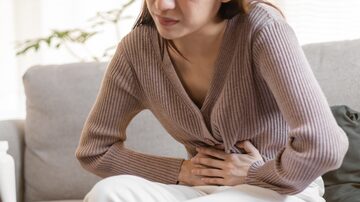 Flatulence young asian woman, girl hand in stomach ache, suffer from food poisoning, abdominal pain and colon problem, gastritis or diarrhoea. Patient belly, abdomen or inflammation, concept. Foto: KMPZZZ/Adobe Stock