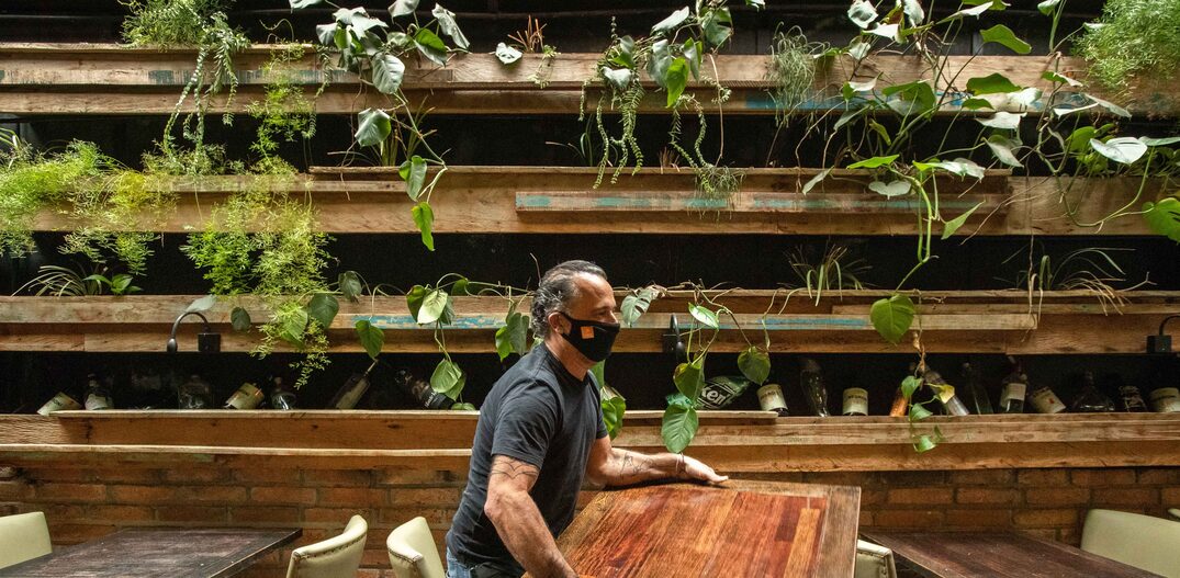 Edrey Momo, proprietario do restaurante Tasca da Esquina, tira mesa entre outras duas para se chegar a distancia de 1,5m entre elas. Foto: Daniel Teixeira/Estadão 
