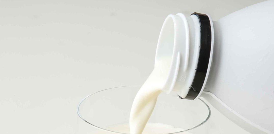 Copo de leite sendo preenchido por leite em garrafa. Foto: Daniel Teixeira | Estadão