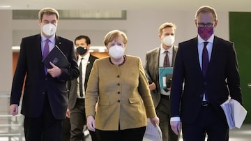 A chanceler Angela Merkel, ao lado do premiê da Bavária, Markus Soeder (esq.) e o prefeito de Berlim, Michael Mueller (dir.). Foto: Michael Kappeler / POOL / AFP