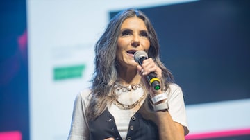 Carla Assumpção aparece com calças pretas e a blusa branca, em cima do palco, em apresentação sobre a Swarovski. Foto: MIQUEIAS @F.5.6_FOTOGRAFIA