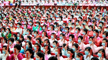 Enfileiradas na plateia, mulheres usam vestidos de cores vivas e máscaras azuis durante o congresso realizado na Coreia do Norte. Foto: EFE/EPA/KCNA