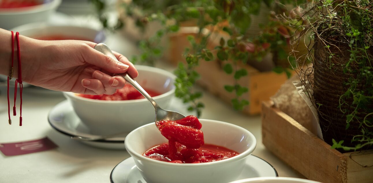 três bowls de porcelana branca com tomates pelados. Mão de mulher com pulseiras vermelhas aparece segurando uma colher com tomates. Foto: DANIEL TEIXEIRA