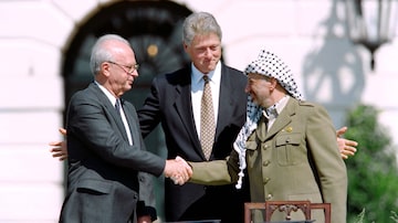 (FILES) US President Bill Clinton (C) stands between PLO leader Yasser Arafat (R) and Israeli Prime Minister Yitzahk Rabin as they shake hands for the first time, on September 13, 1993 at the White House in Washington DC, after signing the historic Israel-PLO Oslo Accords on Palestinian autonomy in the occupied territories. Three decades after a historic handshake on the White House lawn that capped months of secret Israeli-Palestinian talks, disillusioned young Gazans face the consequences and failed promises of the once-celebrated Oslo Accords. (Photo by J. DAVID AKE / AFP)