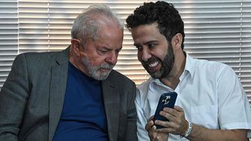 Brazilian presidential candidate for the leftist Workers Party (PT) and former President (2003-2010), Luiz Inacio Lula da Silva (L) looks at a phone hold by ex-presidential canditate for the Avante Party, Andre Janones (R), during a meeting in Sao Paulo, Brazil, on August 4, 2022. - Janones withdrew from running for president in support of Lula da Silva's candidacy. (Photo by NELSON ALMEIDA / AFP)
