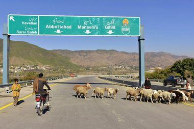 Um motociclista passa por ovelhas em uma estrada recém-construída em Haripur, Paquistão, em 22 de dezembro de 2017. Estrada foi construída com empréstimo da China