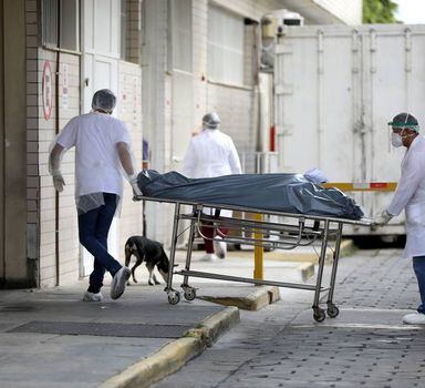 Profissionais da saúde transportam o corpo de uma pessoa em hospital de Manaus