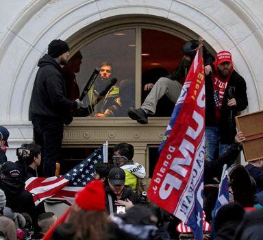 FILE PHOTO: A mob of supporters of then-U.S. President Donald Trump climb through a window they broke as they storm the U.S. Capitol Building in Washington, U.S., January 6, 2021. REUTERS/Leah Millis/File Photo