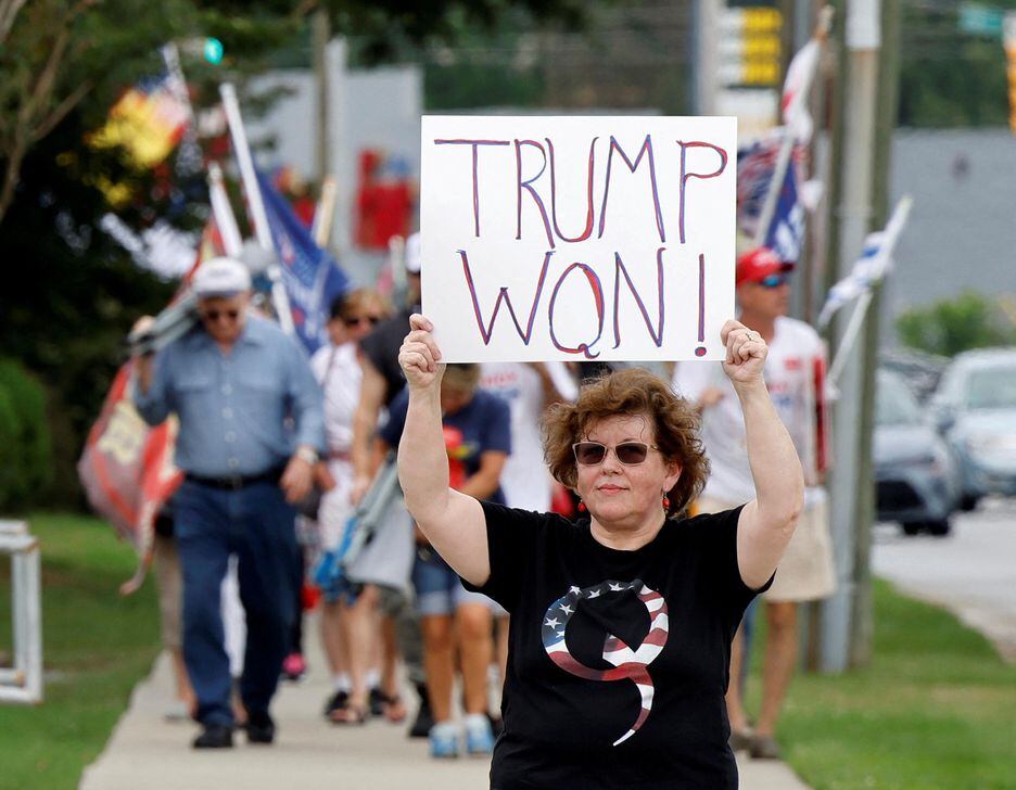Apoiadora do ex-presidente Donald Trump usa camisa do grupo conspiracionista QAnon enquanto segura cartaz afirmando que Trump venceu a eleição presidencial de 2020, durante convenção do Partido Republicano na Carolina do Norte.